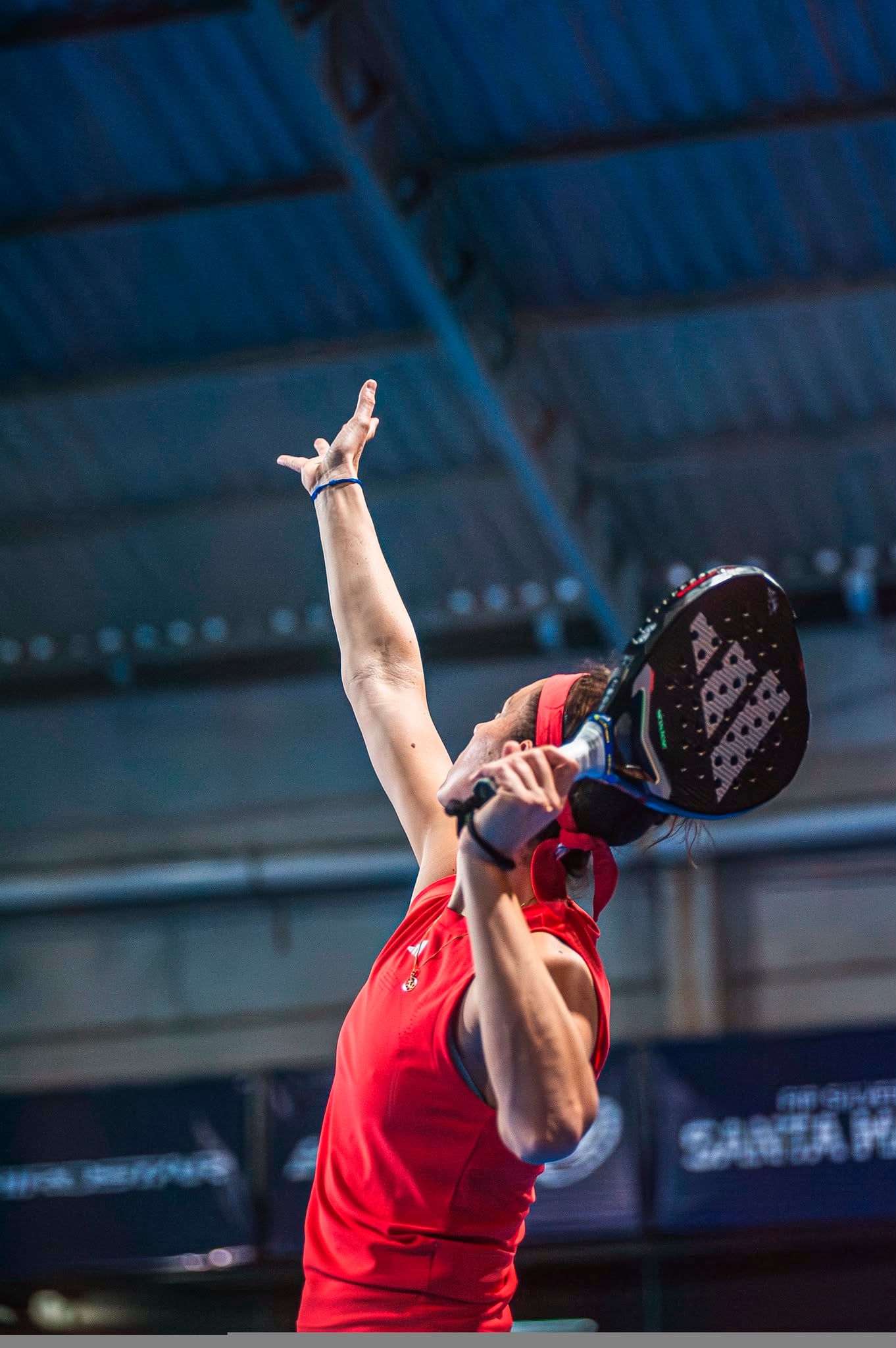 Padelspeelster slaat een service tijdens een indoor wedstrijd